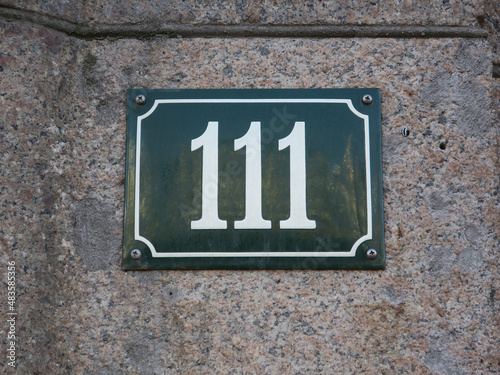 housenumber 111 on an enamel sign on a stone wall