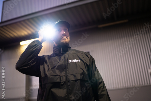 Security Guard Walking Building Perimeter With Flashlight