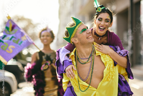Playful couple have fun while piggybacking on Mardi Gras street parade during the festival.