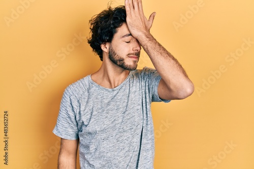 Handsome hispanic man wearing casual grey t shirt surprised with hand on head for mistake, remember error. forgot, bad memory concept.