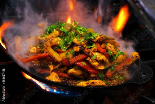 mexican food, chicken fajitas preparing on a hot smoking sizzling plate