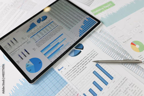 On statistical reports lies a tablet with charts on the screen