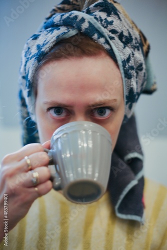 Woman with a towel on her head drinking coffee