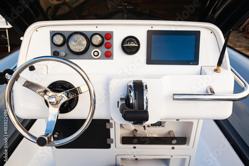 Boat control cabin with instrument panel, steering wheel and radio station.