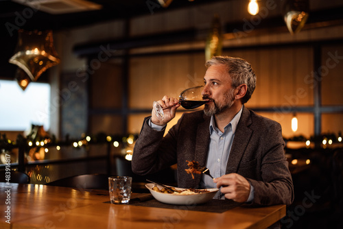 Serious caucasian food critic, enjoying the quality food in a restaurant.