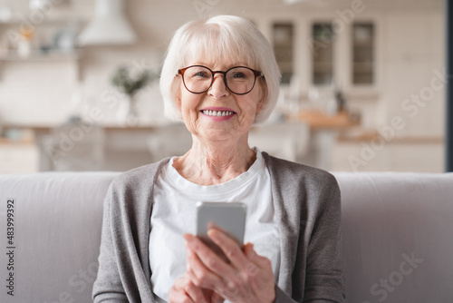 Closeup cropped front view photo of senior old elderly caucasian woman grandmother using smart phone cellphone for e-banking e-commerce, surfing social media online at home