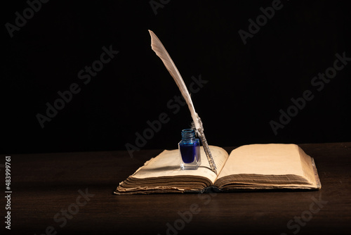 Quill pen and inkwell resting on an old book concept for literature, writing, author and history