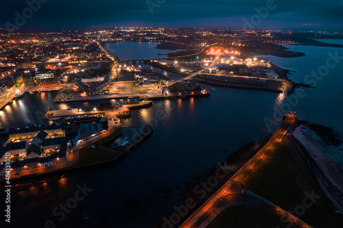 Galway city illuminated at night, the port area. Aerial high point view. Dark scene. Town at night. Popular travel destination. Business and educational center. City lights glow in the dark.