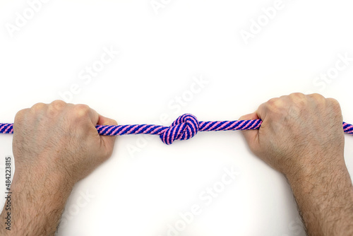 Male hands firmly hold a rope with a knot on a white background close-up. The concept of willpower or a person in a difficult situation. The man has given up a bad habit. Strong hands tighten the knot