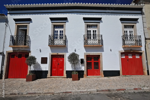 Whitewashed facade-vernacular townhouse-red doors-four balconies with wrought iron railings. Tavira-Portugal-069