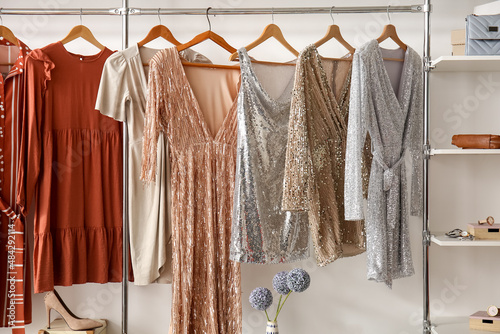 Stylish dresses hanging in wardrobe in dressing room