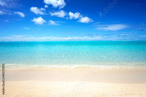 Beautiful sandy beach with white sand and rolling calm wave of turquoise ocean on Sunny day. White clouds in blue sky. Perfect tropical seascape, copy space.
