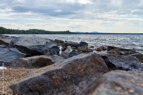 stones on the shore of a lake overgrown with forest