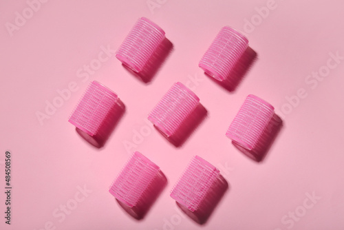 Set of hair curlers on pink background