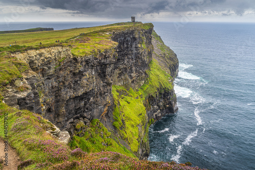 Tourists on a trail to Moher Tower on iconic Cliffs of Moher, popular tourist attraction, UNESCO world heritage, Wild Atlantic Way, Clare, Ireland