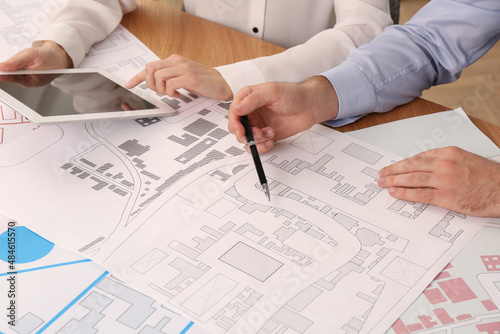 Professional cartographers working with cadastral map at table, closeup