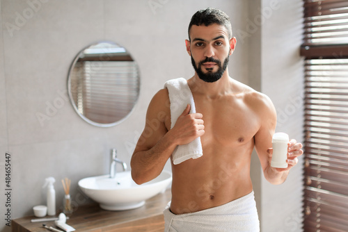 Handsome young guy standing with shampoo and deodorant bottle