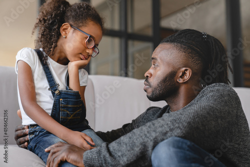 Loving african-american father dad listening to daughter`s problems with attention, supporting and calming her at home. Solving family problems. Fatherhood.