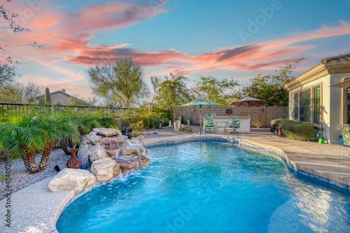 Luxury home pool at sunset with a waterfall