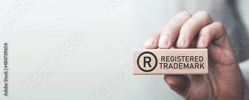 Male hand showing R-Registered trademark on wooden block.