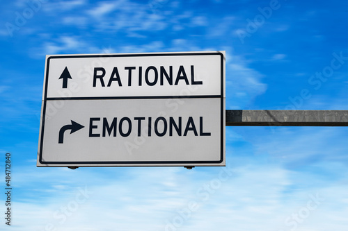 Road sign with words rational and emotional. White two street signs with arrow on metal pole on blue sky background.