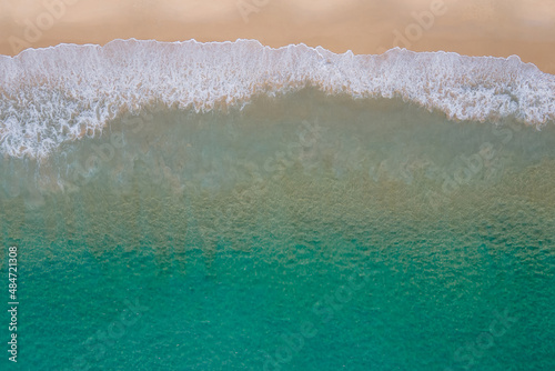 Aerial view of turquoise ocean wave reaching the coastline. Beautiful tropical beach from top view. Andaman sea in Thailand. Summer holiday vacation concept