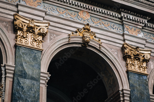 Arch and pilasters with gold Corinthian capitals inside the Jesuit Cathedral in Lviv, Ukraine. Medieval interior design concept.