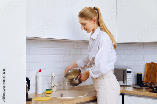 Young woman draining cooked spaghetti with colander