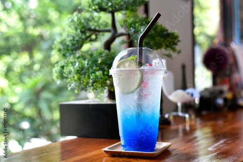 Closeup glass of blue lagoon cocktail decorated with lime at bar counter beverage shop background. Cold drinks and cocktails in summer. selected focus