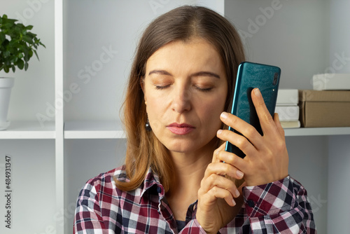 Blind woman holding mobile phone using speakerphone.