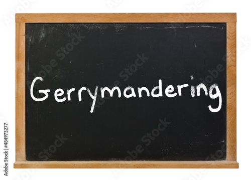 Gerrymandering written in white chalk on a black chalkboard isolated on white