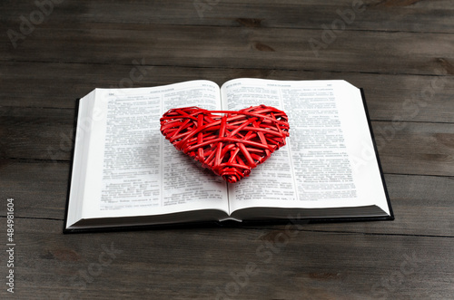 Open book, Bible. On the table. Red heart. The concept of love for God and Scripture.