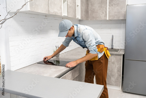 Master installs electric hob on kitchen cabinet.