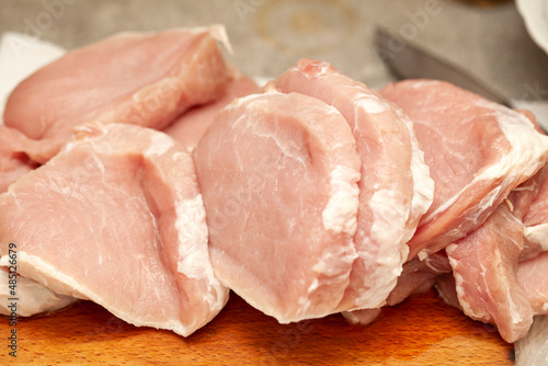 Lots of uncooked fresh juicy raw fat pork chop meat pieces, freshly cut up, food, object closeup, nobody. Unprocessed pig meat, raw chops set, loin cuts up close, kitchen scene, nutrition concept