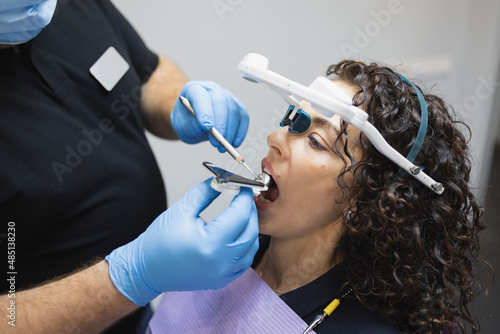 Doctor orthodontist installs a system for diagnosing jaw joints and occlusion for a woman patient