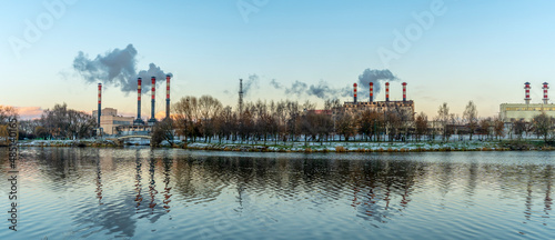 Smoking chimneys of a thermal power plant against a winter cloudy sky. Ecological problems concept. Space for text.