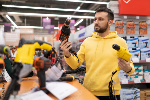 a buyer in a construction hypermarket chooses a drill by comparing two models with each other