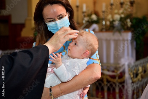 The pastor baptizes a child in the church using holy water