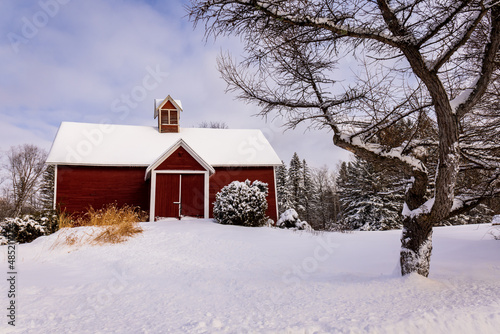 The village of Stanbrige-East, in the Eastern Townships, an old wooden barn painted red, with the land covered with snow.