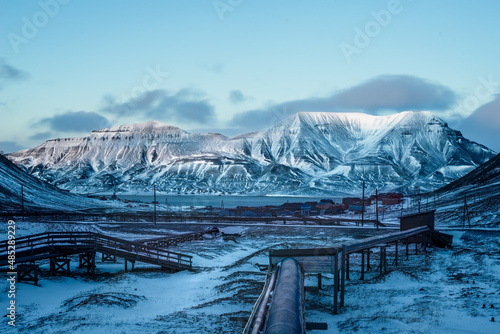 landscape with mountains and sky. The collective heating pipes are insulated from the ground to protect the permafrost