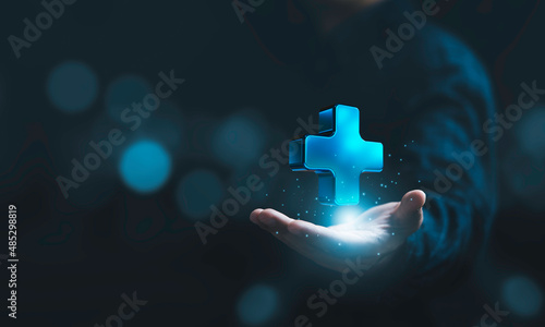 Businessman holding virtual blue plus sign for positive thinking mindset or healthcare insurance symbol concept.