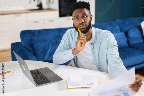 Intelligent pensive businessman involved virtual meeting on the laptop while sitting in modern office. Confident modern businessman in casual wear holding educational course