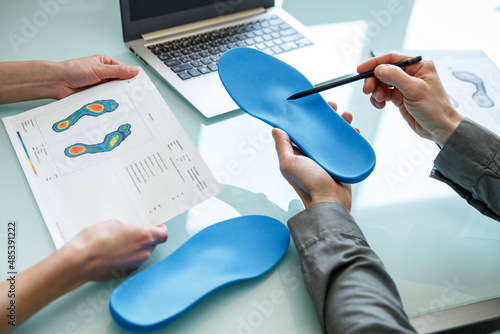 Doctor consulting patient on custom orthotic insoles in a clinic for a personalised custom fit.