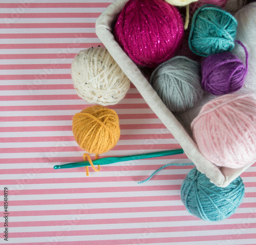colorful woolen balls with crochet hooks on colorful ground with pattern