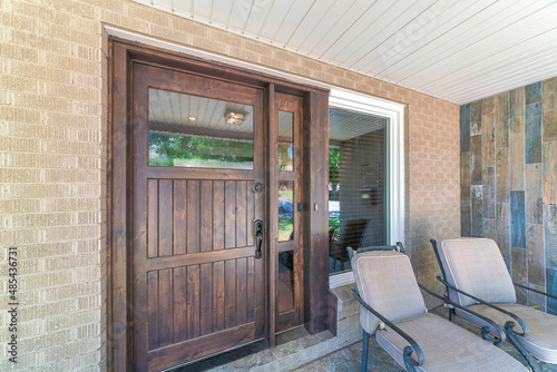 Dark wood front door with glass panel and sidelight near the picture window