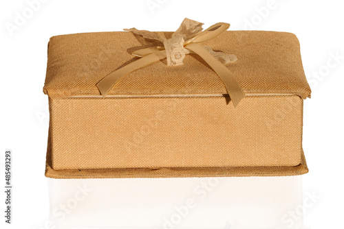 A Gift Box With A Shadow. A golden-colored jewelry gift box with a textured fabric lining with a jar highlighted on a white background