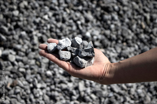 hand holding handful of crushed grey stones