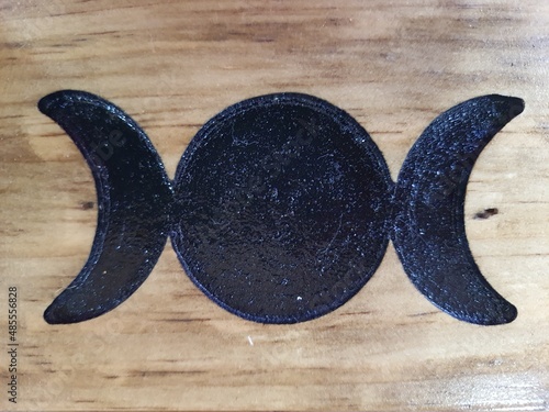 Symbol of the triple goddess, moon phases, carved on a wooden surface. Maiden, Mother and Crone. Mythology, Wicca, Witchcraft, Bruaria, Pagan Religion and Philosophy of Life.