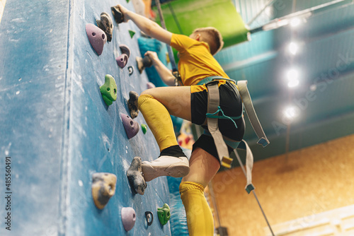 Teenage boy at indoor climbing wall. Kid having fun at bouldering wall. Child learning at climbing class. Sports healthy lifestyle. Youth at climbing summer camp
