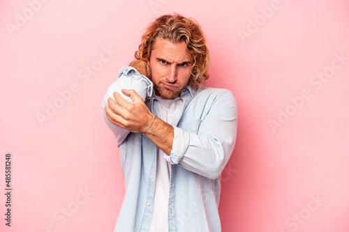 Young caucasian man isolated on pink background having a neck pain due to stress, massaging and touching it with hand.